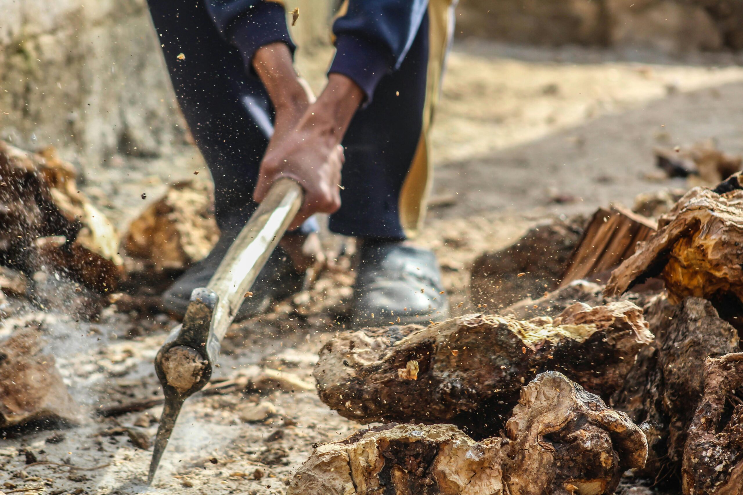 Close-up of a person chopping wood outdoors with an axe in Syria, capturing dynamic motion.