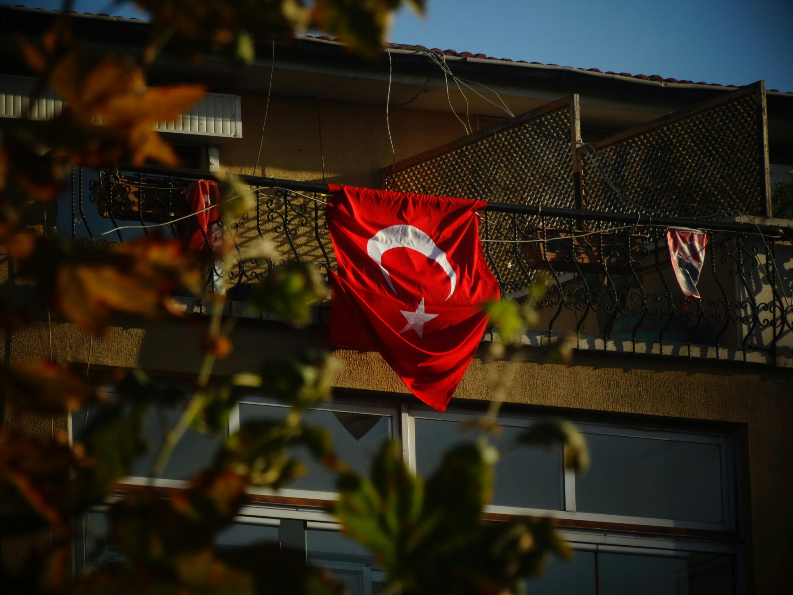 Turkish flag displayed on a balcony in Ankara, Türkiye, featuring natural shadows and colors.