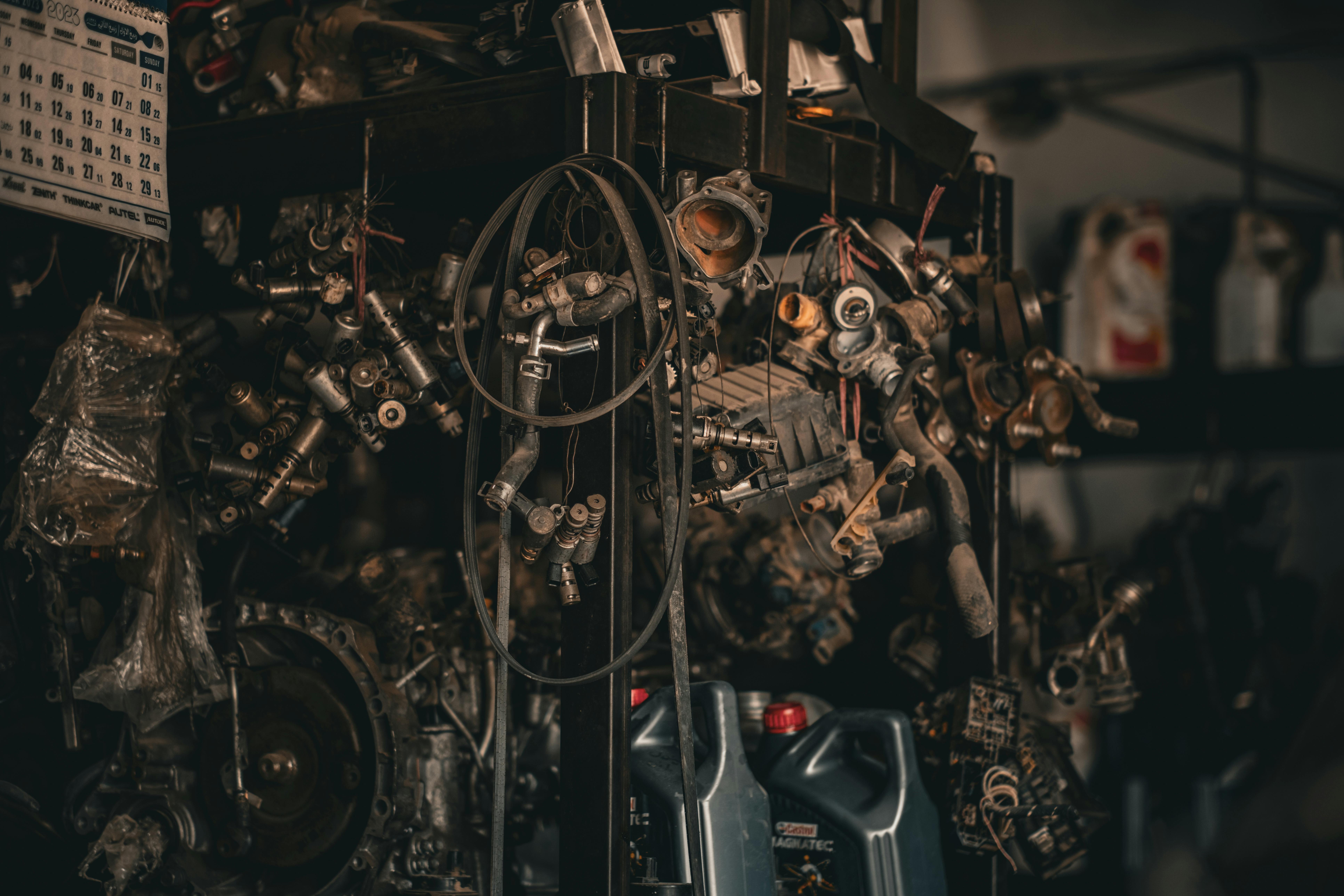 A cluttered auto workshop with various mechanical parts hanging in a dimly lit environment.