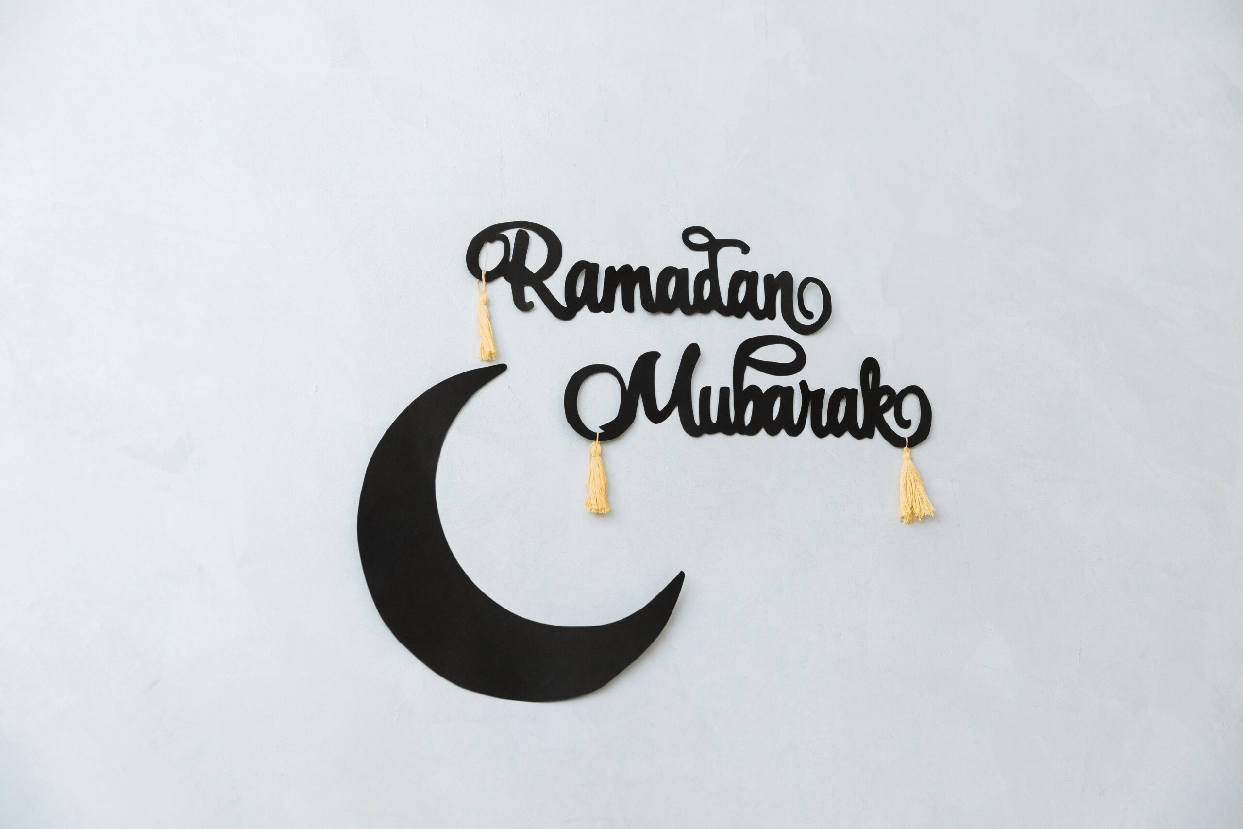 Minimalist Ramadan Mubarak decoration with crescent on a light wall background.